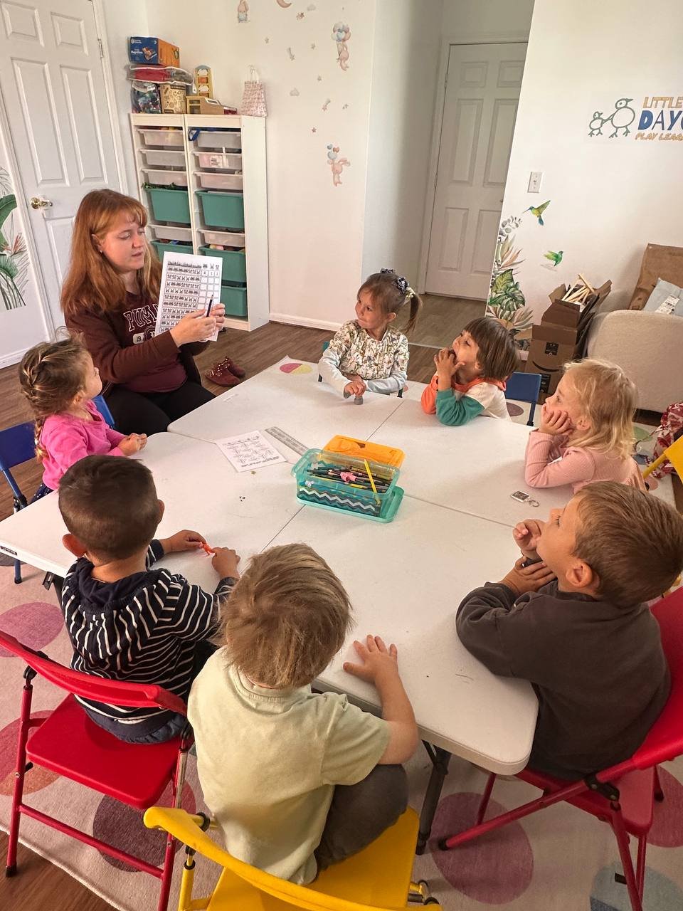 Teacher leading a numbers and counting activity with children around a table at Little Birds LA